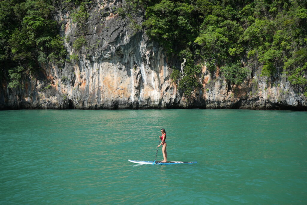 Customer paddleboarding with limestone island in the background, Phang Nga Bay